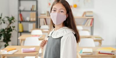 A schoolgirl in a classroom wearing a face mask, symbolizing new normal education.